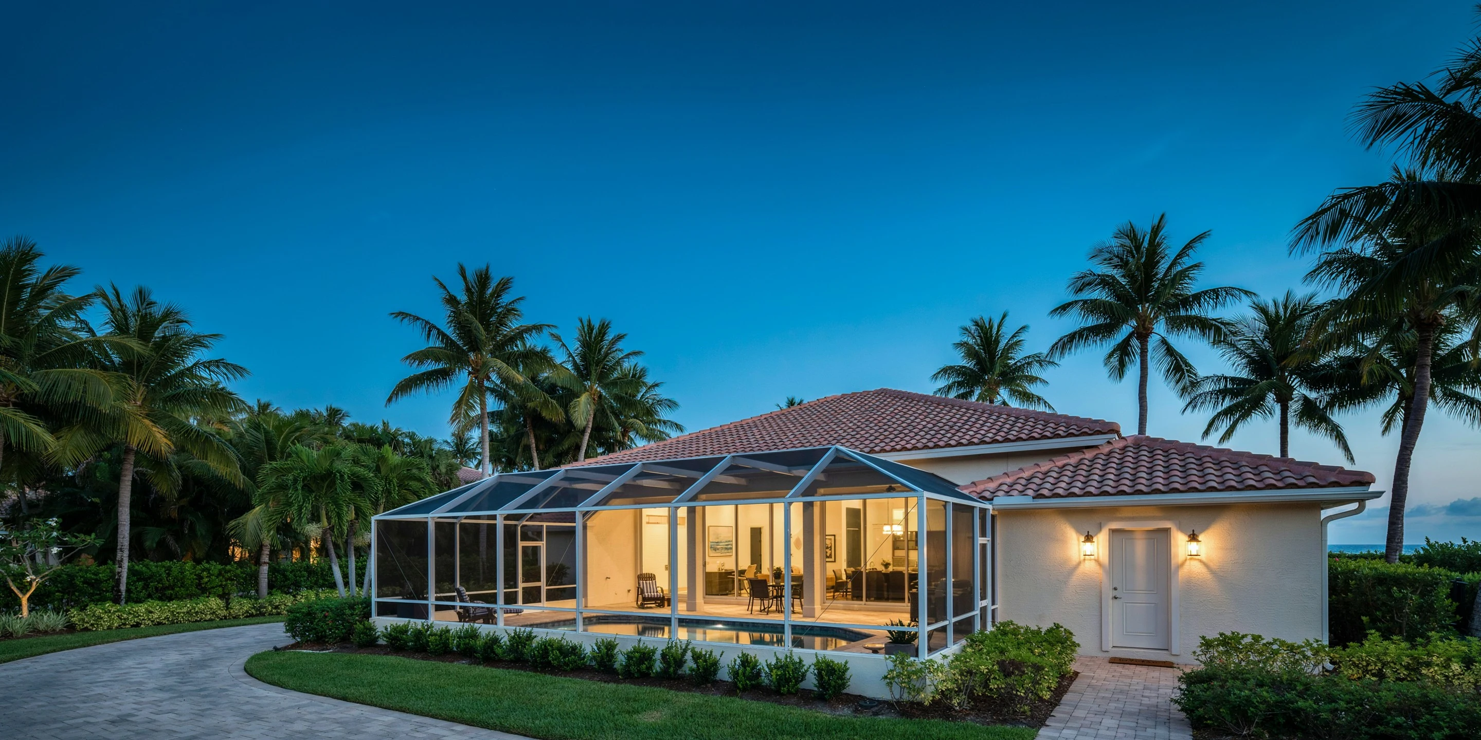 Coastal Sarasota home with a pool cage at blue hour