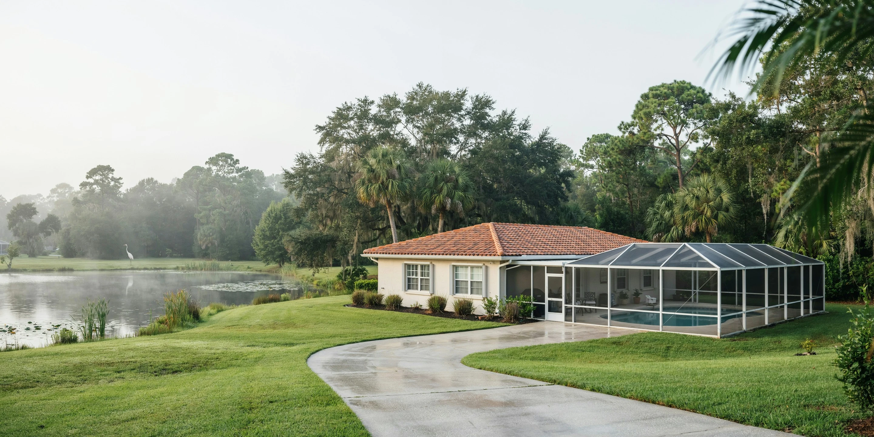 Home with pool cage beside a pond in Sarasota Springs, FL